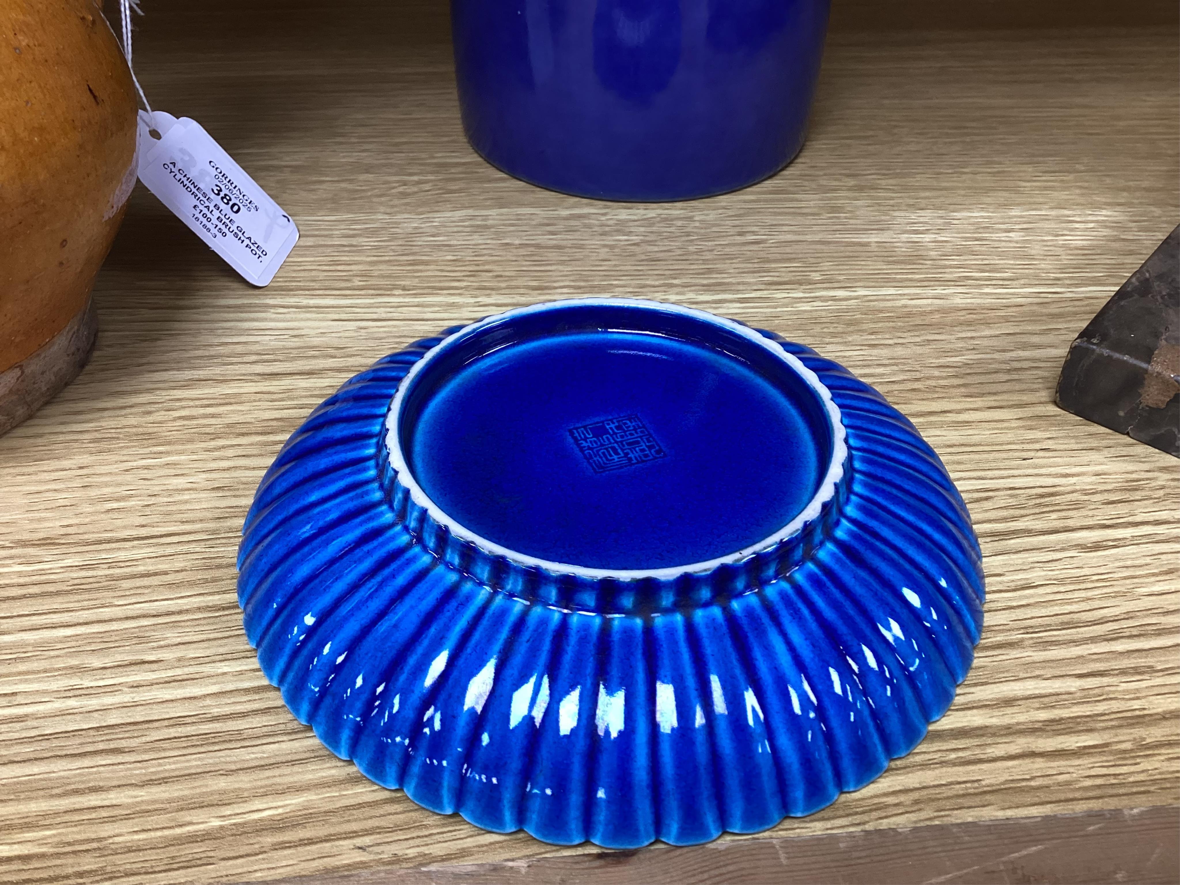 A Chinese blue glazed cylindrical brush pot, Kangxi mark but later, a similar saucer, Qianlong mark but later and a terracotta jug, 21cm